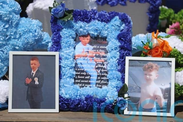 One mourner carried a red and blue helmet while among the floral tributes on the back of a flatbed lorry was a framed picture of the young boy on a bike.