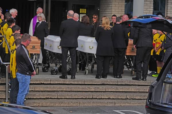 The coffins are brought into the Sacred Heart Parish Centre on Sunday afternoon